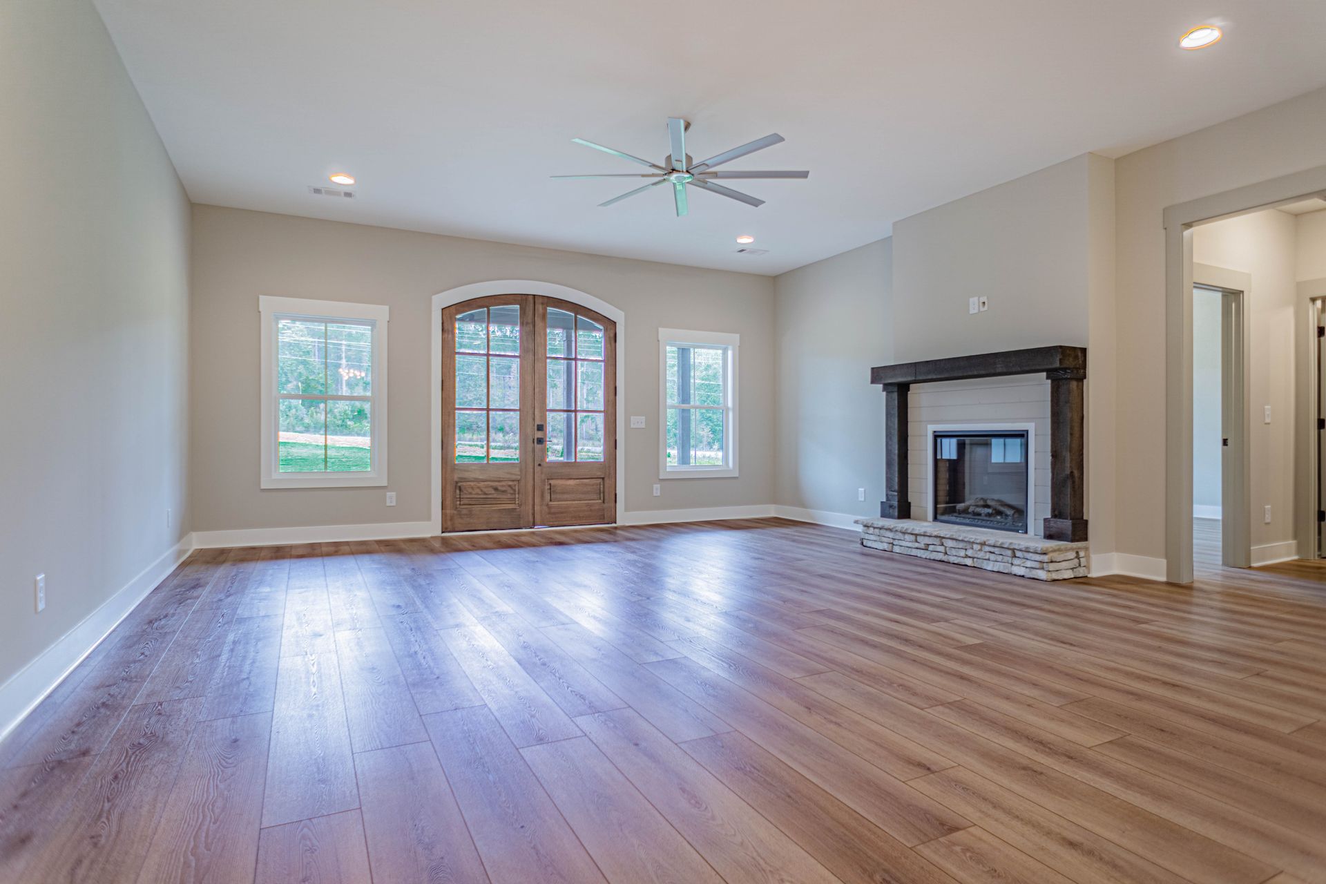 An empty living room with hardwood floors and a fireplace.