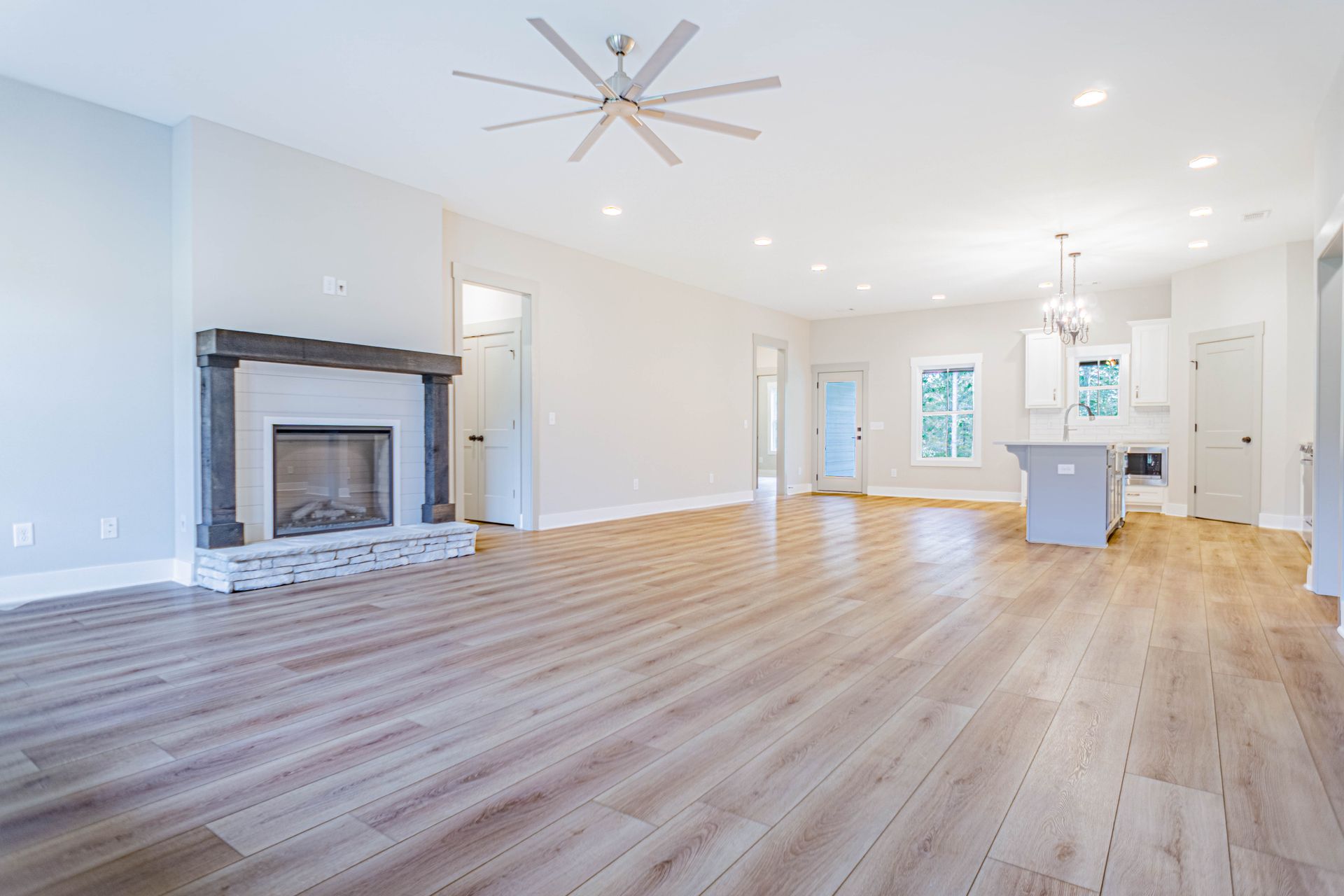 An empty living room with a fireplace and a ceiling fan.