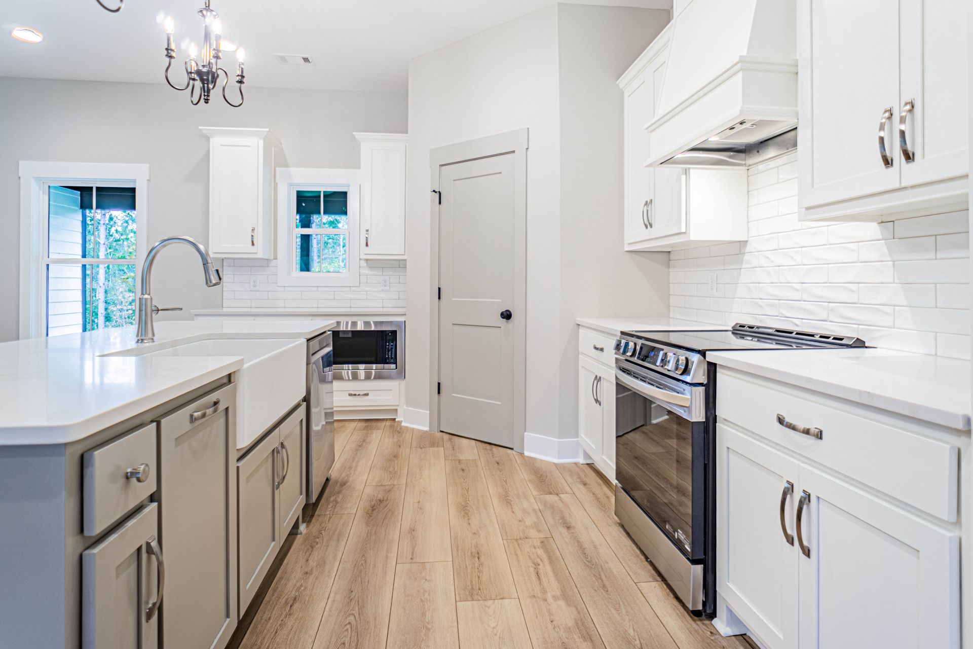 A kitchen with white cabinets , stainless steel appliances , and hardwood floors.