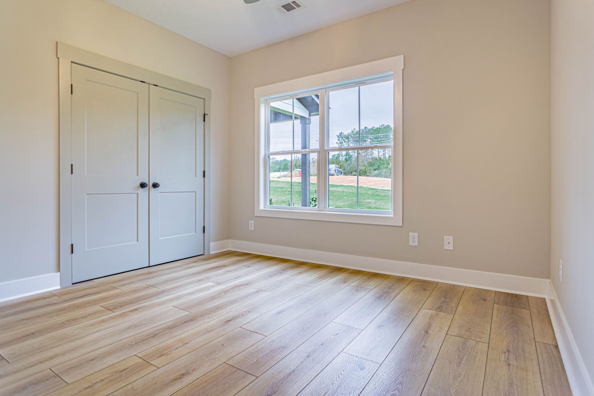 An empty room with hardwood floors and two windows.