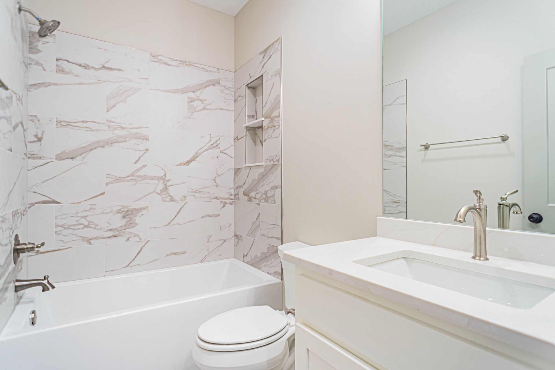 A bathroom with a toilet , sink , bathtub and mirror.