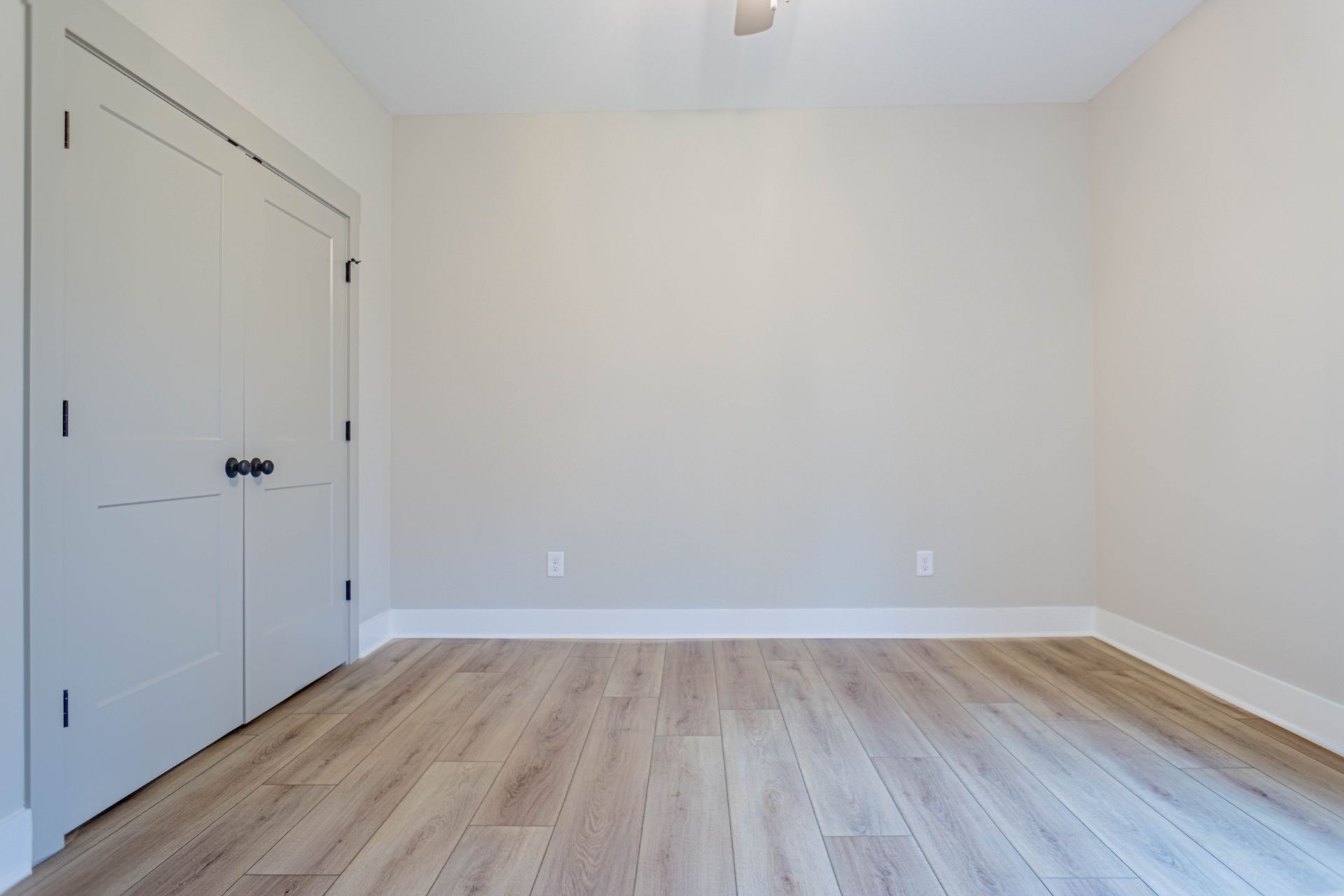 An empty room with hardwood floors and white walls.