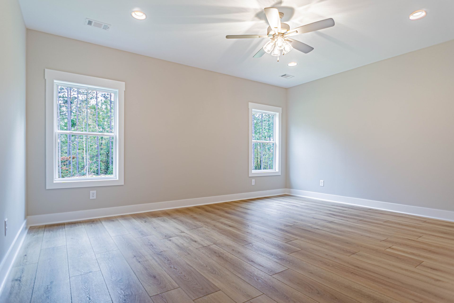 An empty room with hardwood floors and a ceiling fan.