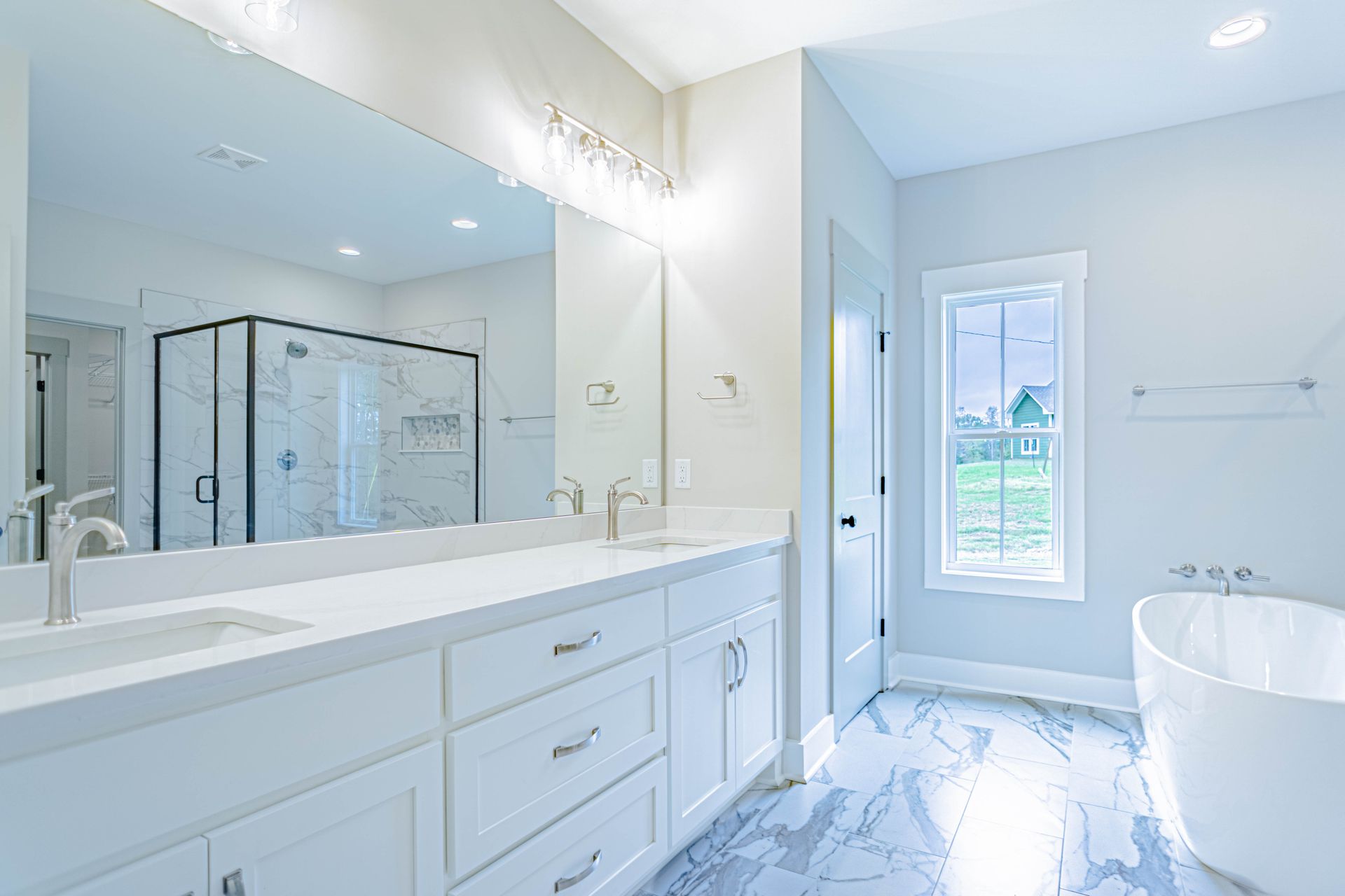 A bathroom with two sinks , a tub , and a large mirror.