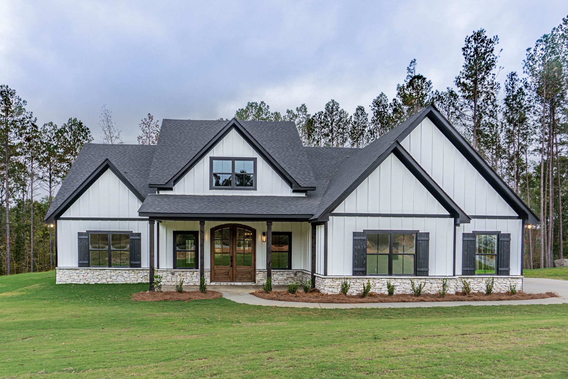 A large white house with a black roof is sitting on top of a lush green field.