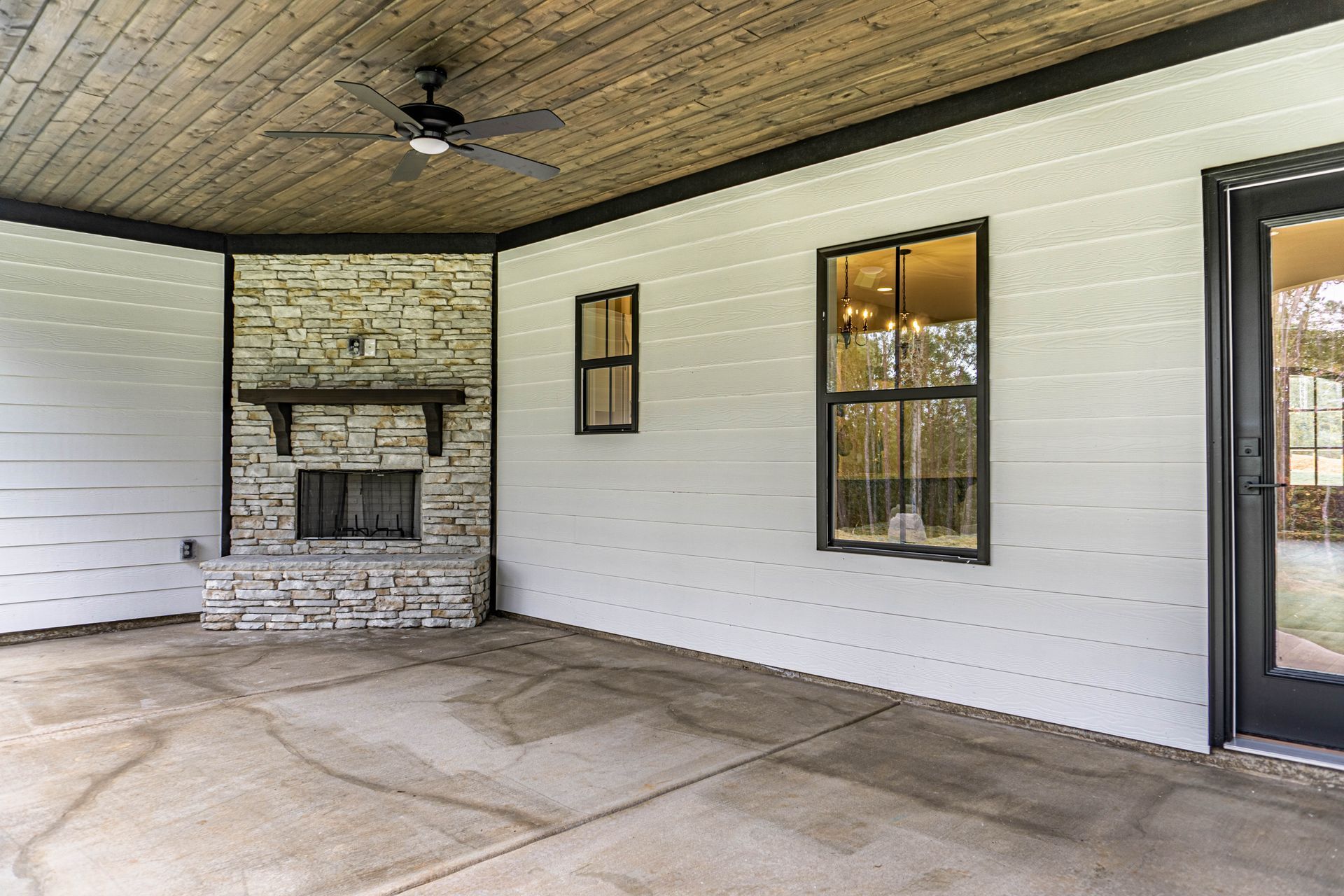 A patio with a fireplace and a ceiling fan.