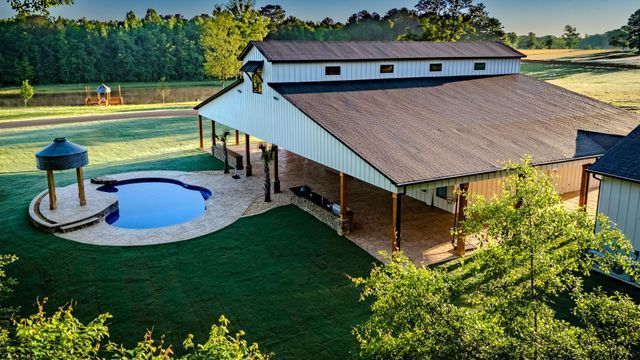 An aerial view of a barn with a pool in the backyard