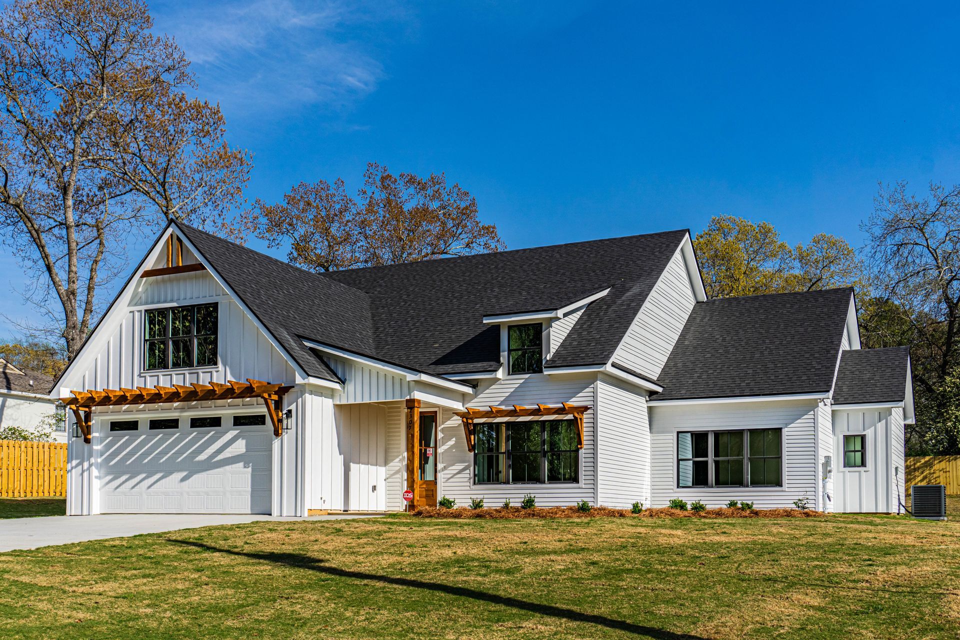 A white house with a black roof is sitting on top of a lush green field.