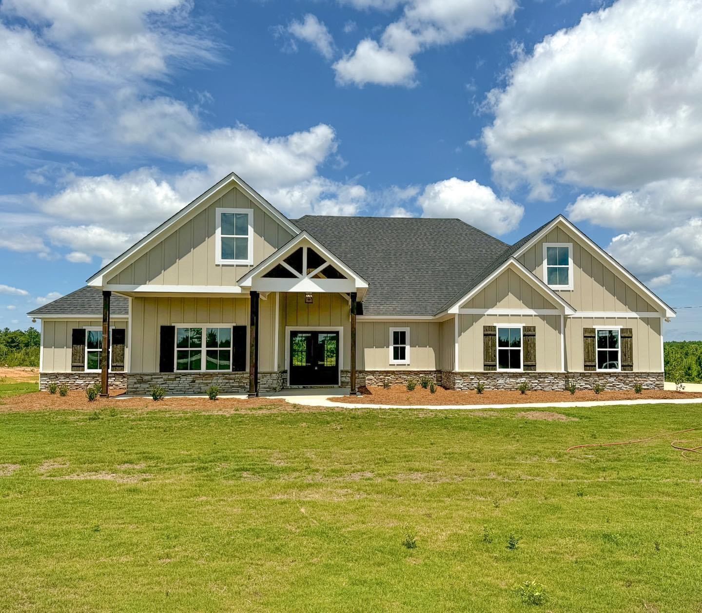 A large house is sitting in the middle of a lush green field.