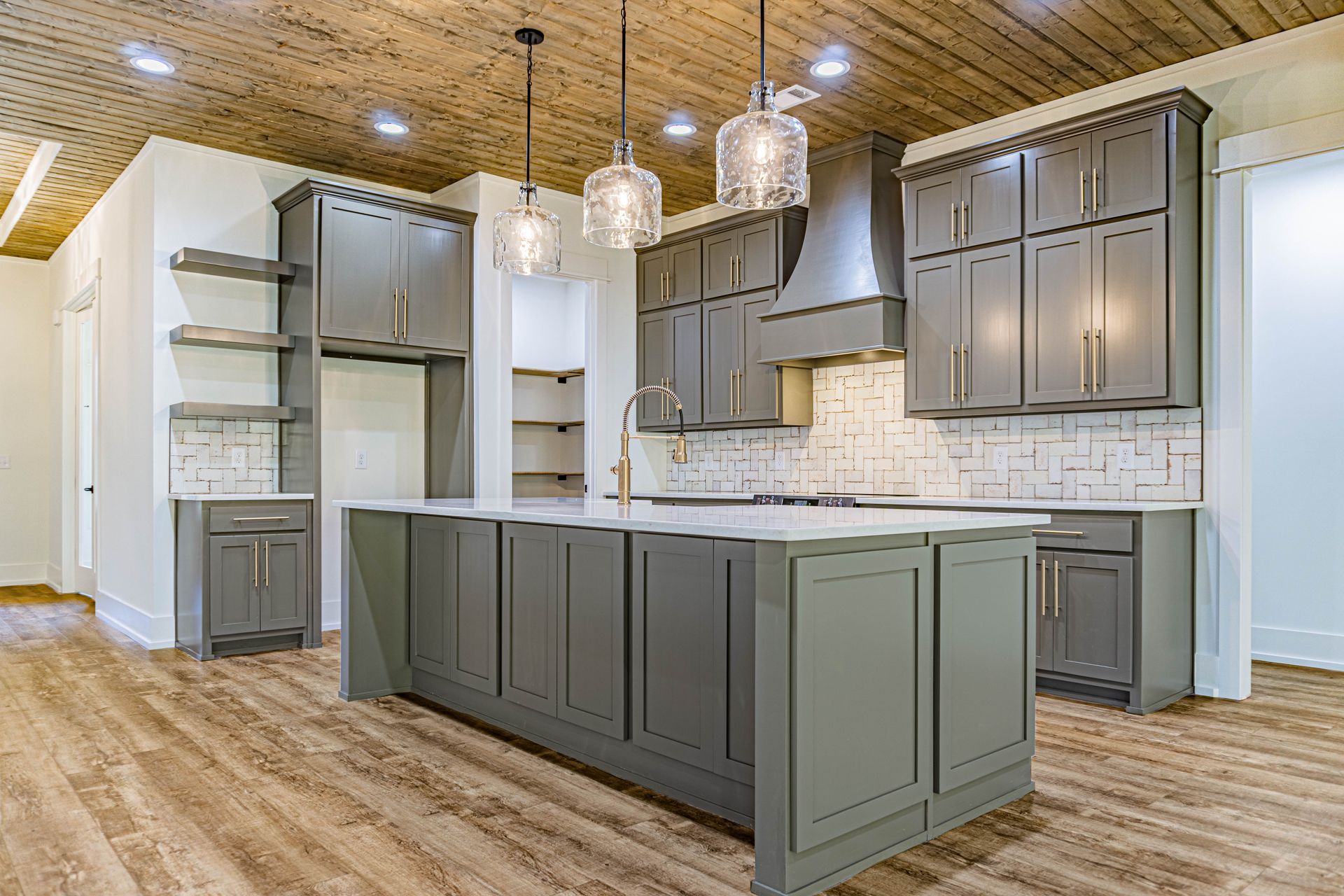A kitchen with gray cabinets and a large island in the middle.