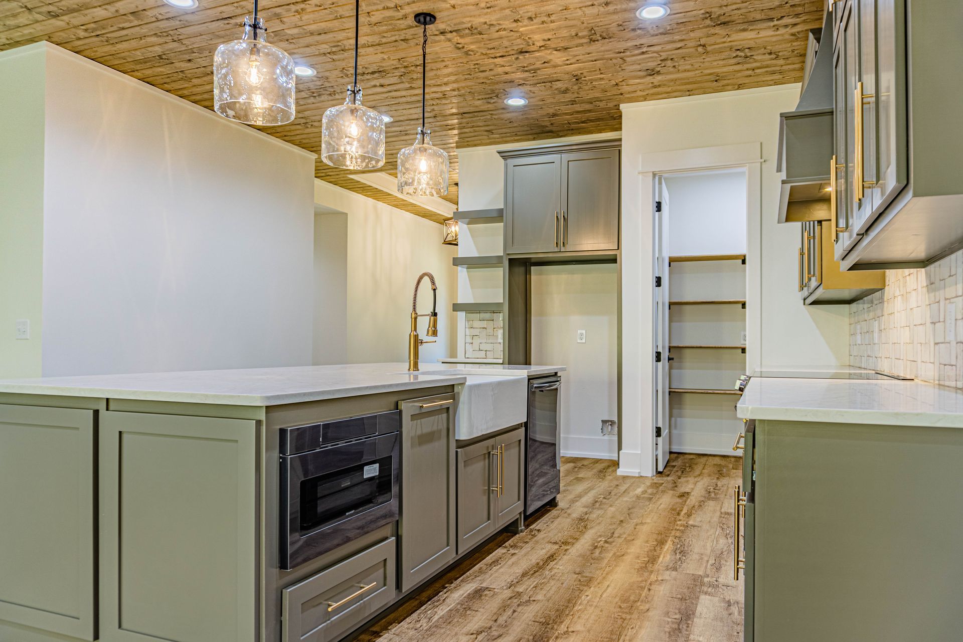 A kitchen with gray cabinets and a wooden floor.