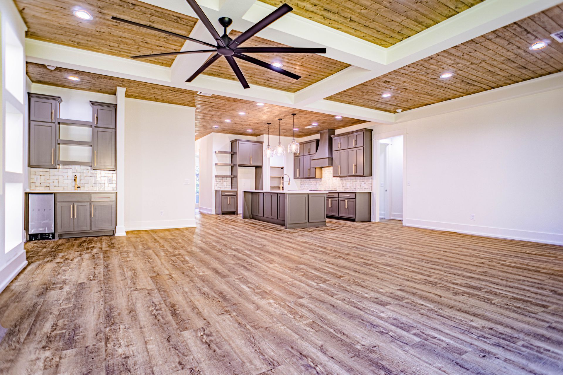 A large empty room with hardwood floors and a ceiling fan.