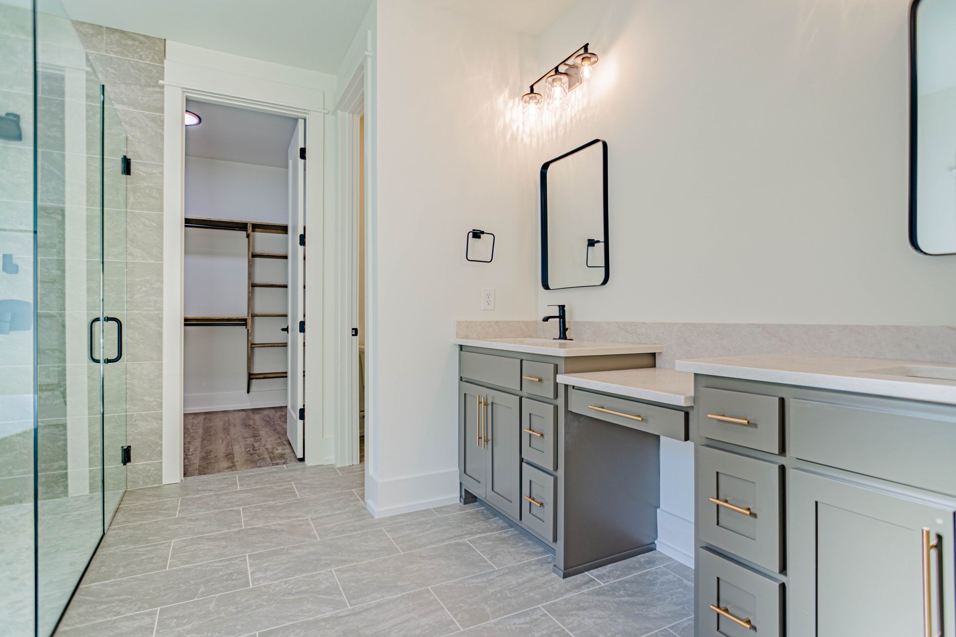 A bathroom with two sinks and a walk in closet.