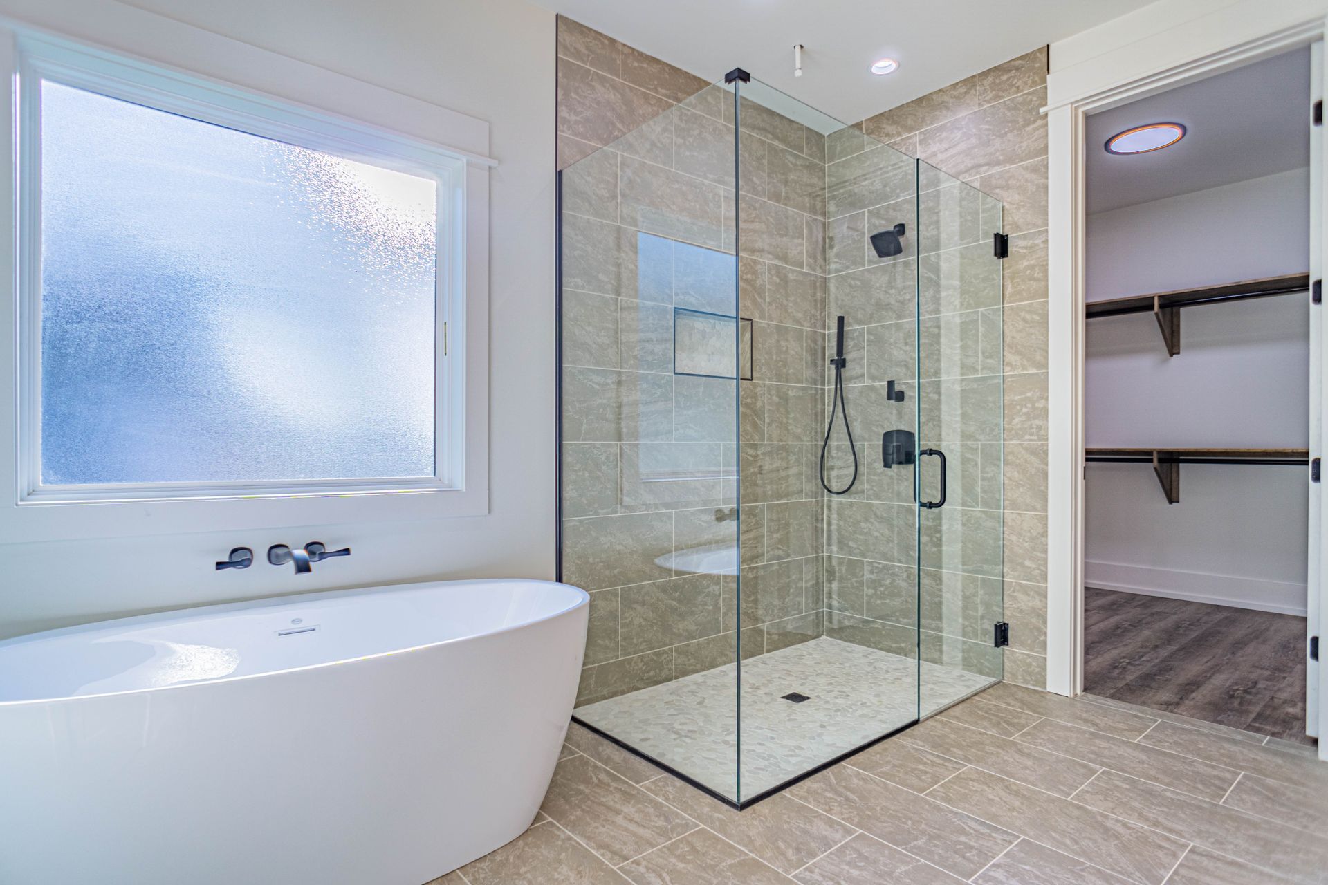 A bathroom with a walk in shower , tub , and window.