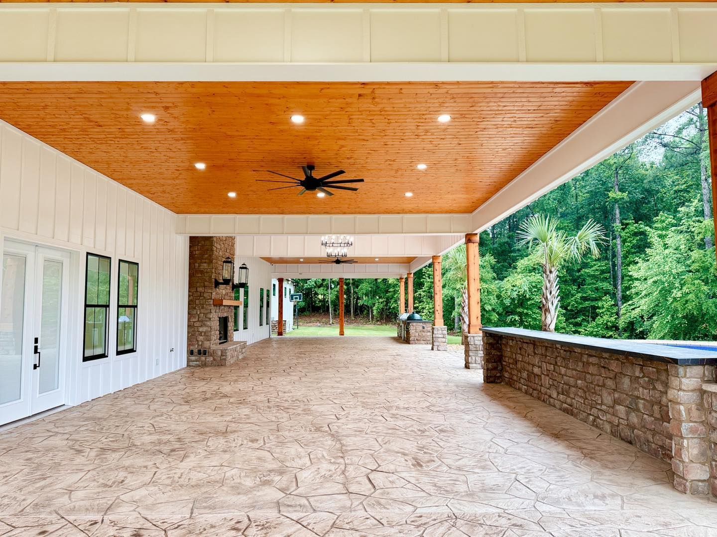 A large covered porch with a wooden ceiling and a ceiling fan.