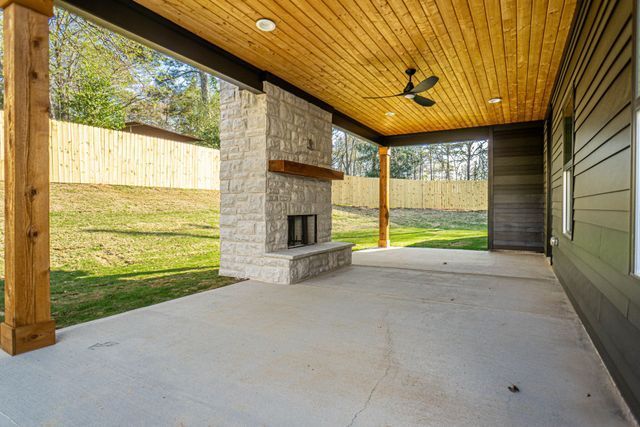 A patio with a fireplace and a ceiling fan.
