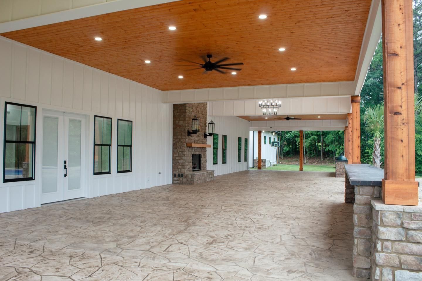 A large covered porch with a ceiling fan and a fireplace.
