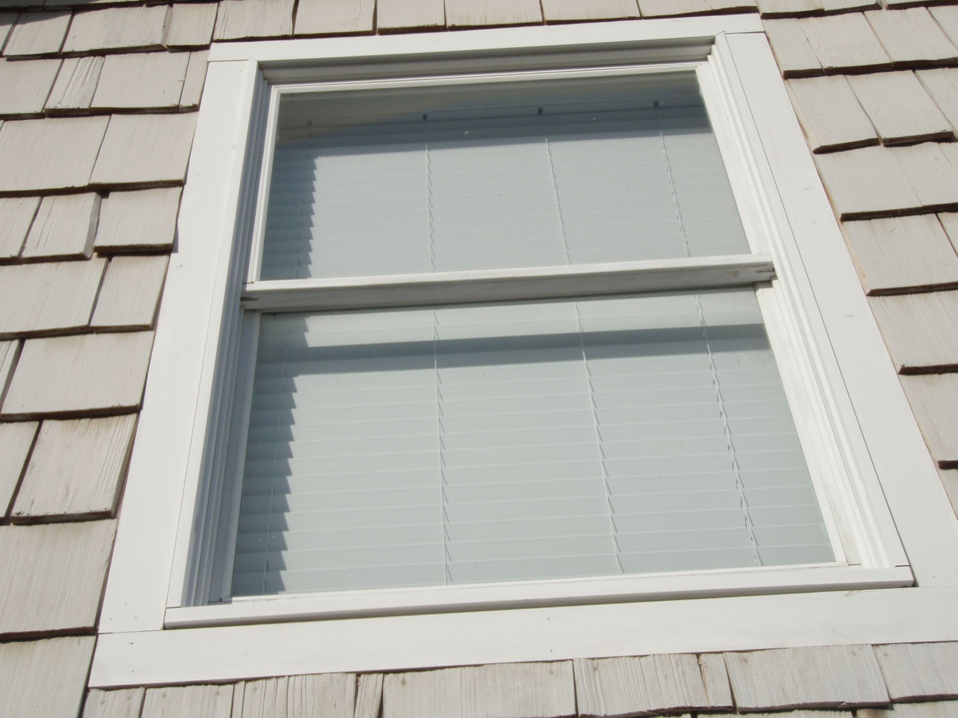 Double-hung window with white vinyl frame and white venetian blinds 