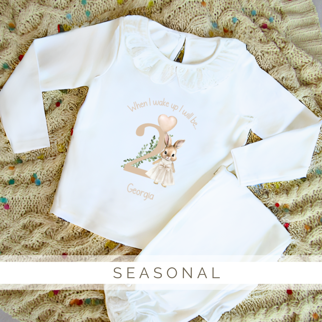 A white shirt with a rabbit on it is laying on a blanket.