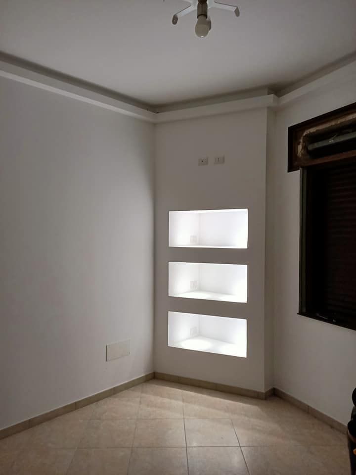 Una stanza vuota con tre scaffali e una finestra