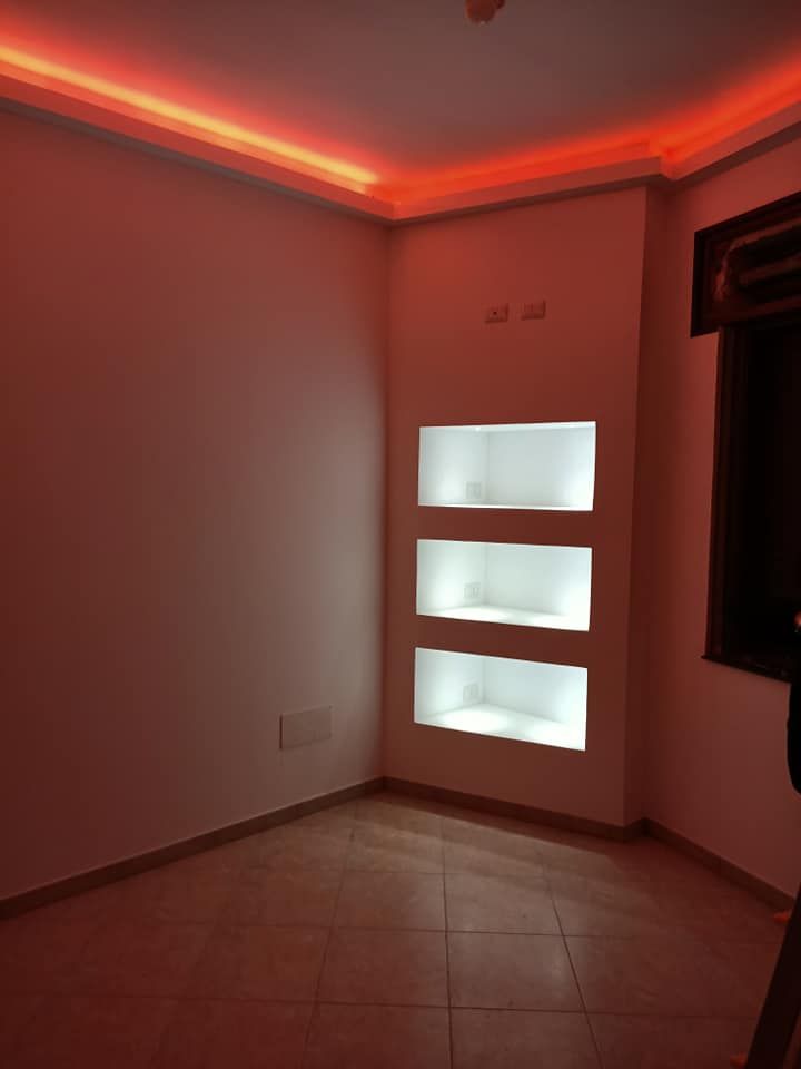 Una stanza con tre scaffali e luci rosse sul soffitto