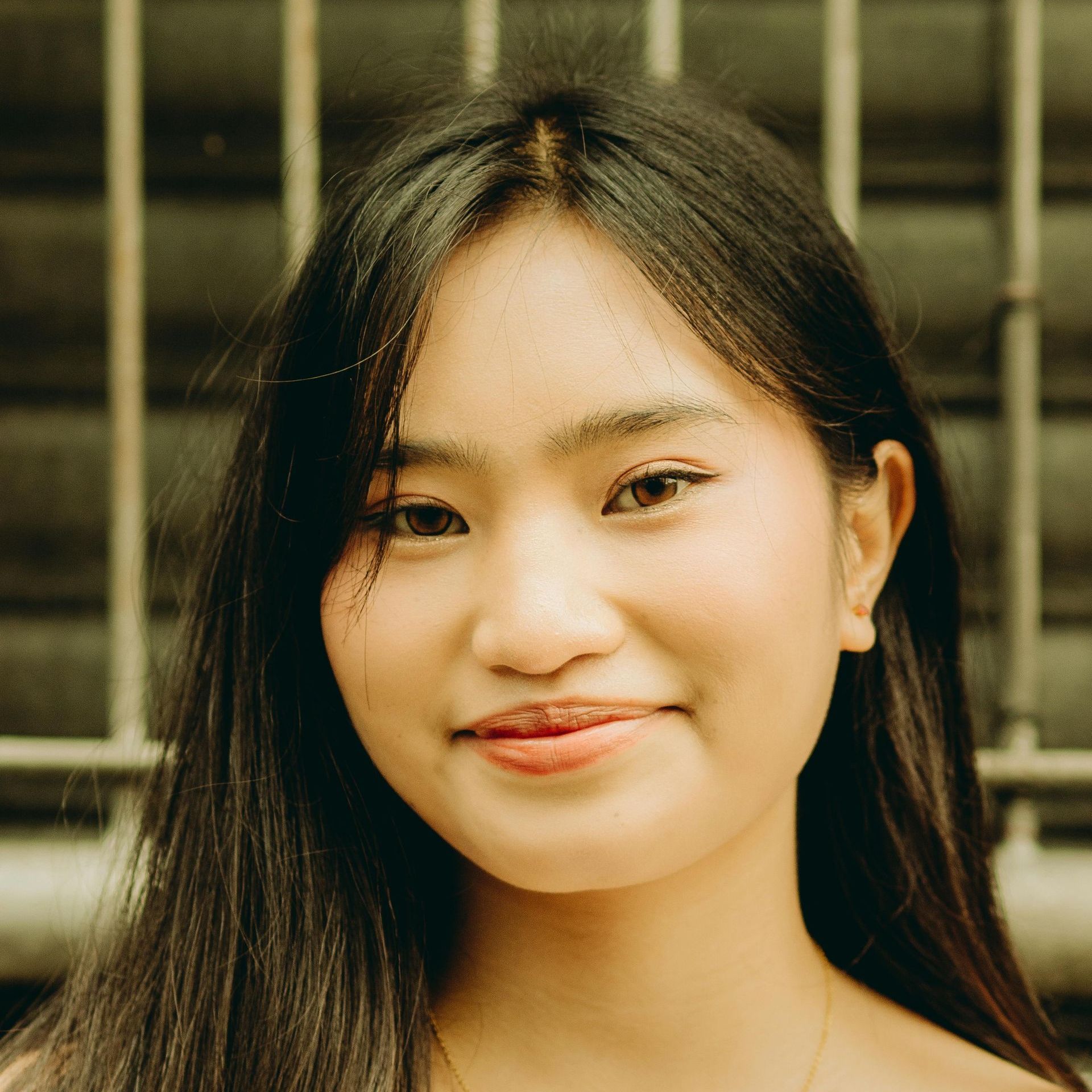 A close up of a woman 's face with a fence in the background.