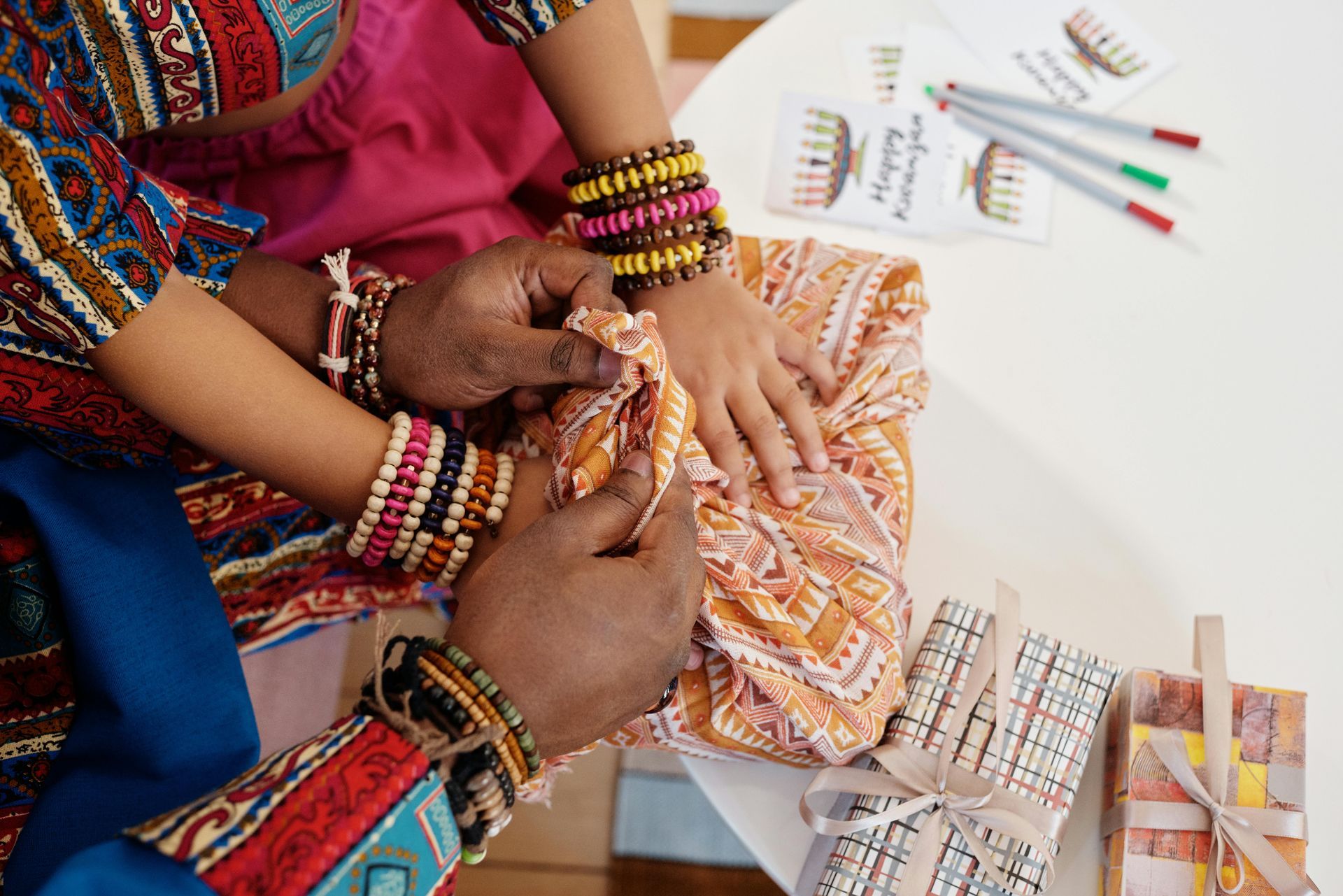 A woman and a child are sitting at a table with bracelets on their hands.