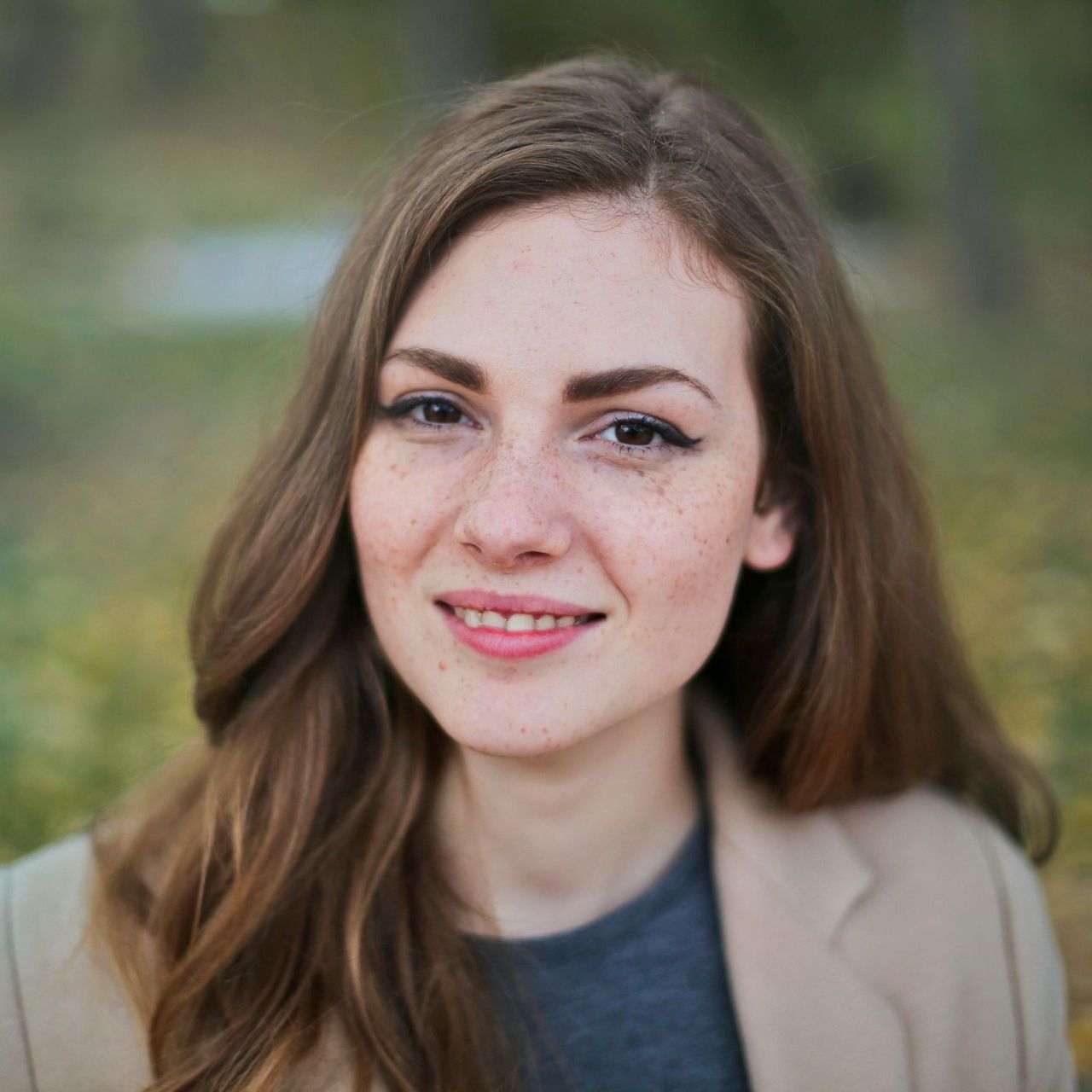 A woman with long brown hair and freckles is smiling for the camera.
