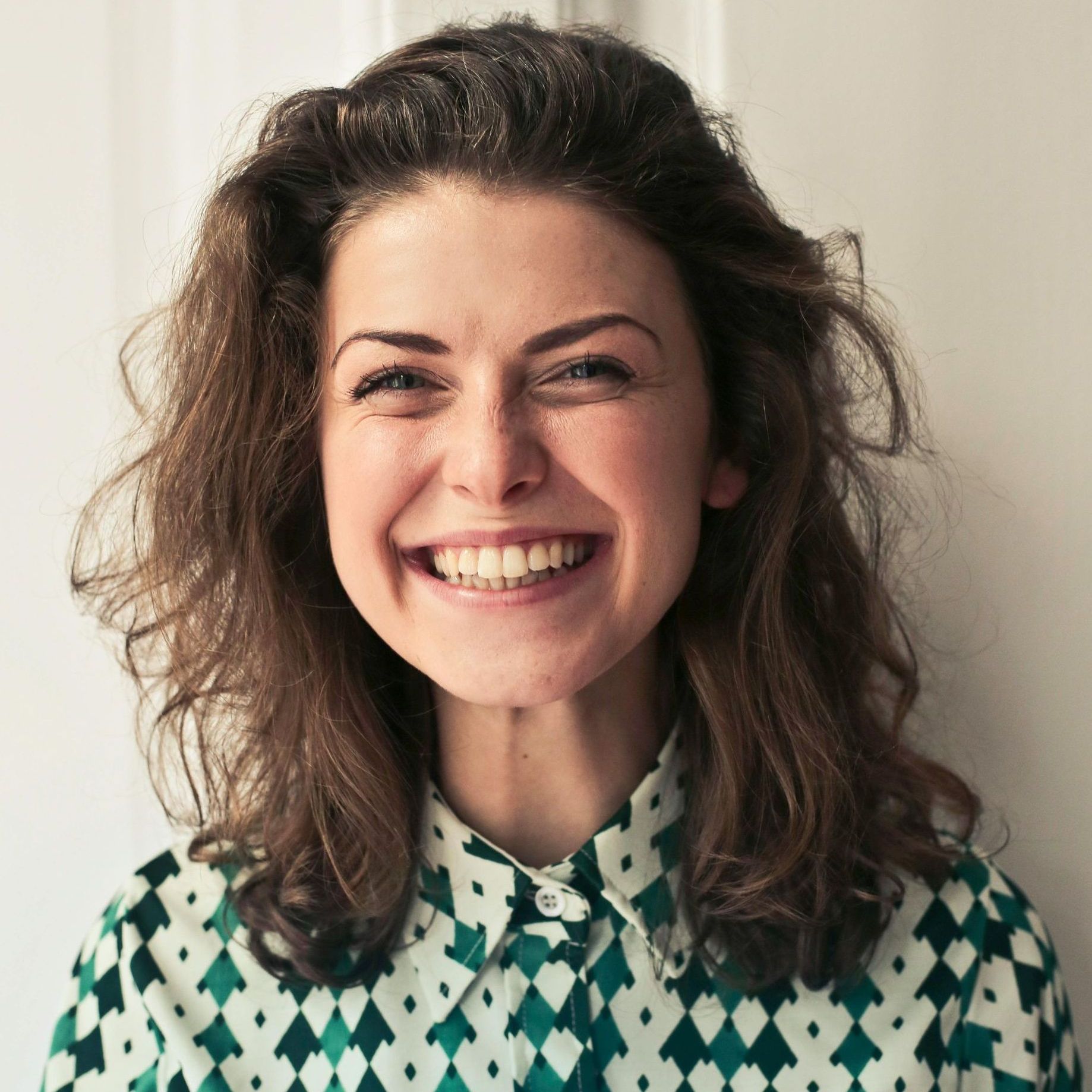 A woman wearing a green and white checkered shirt is smiling