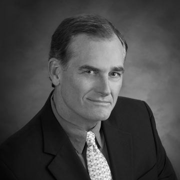 A man in a suit and tie is smiling in a black and white photo