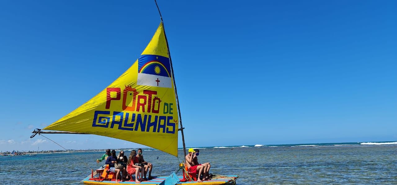 Um grupo de pessoas está andando de barco no oceano com uma vela amarela.