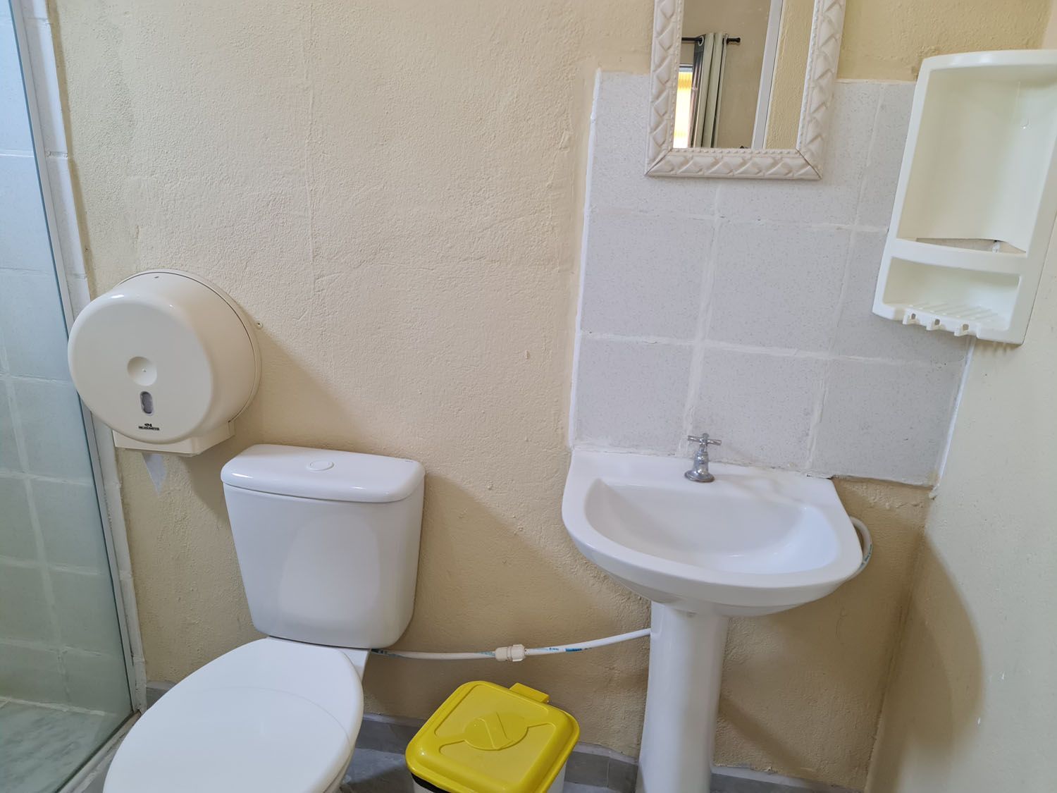 Um banheiro com vaso sanitário, pia e espelho.