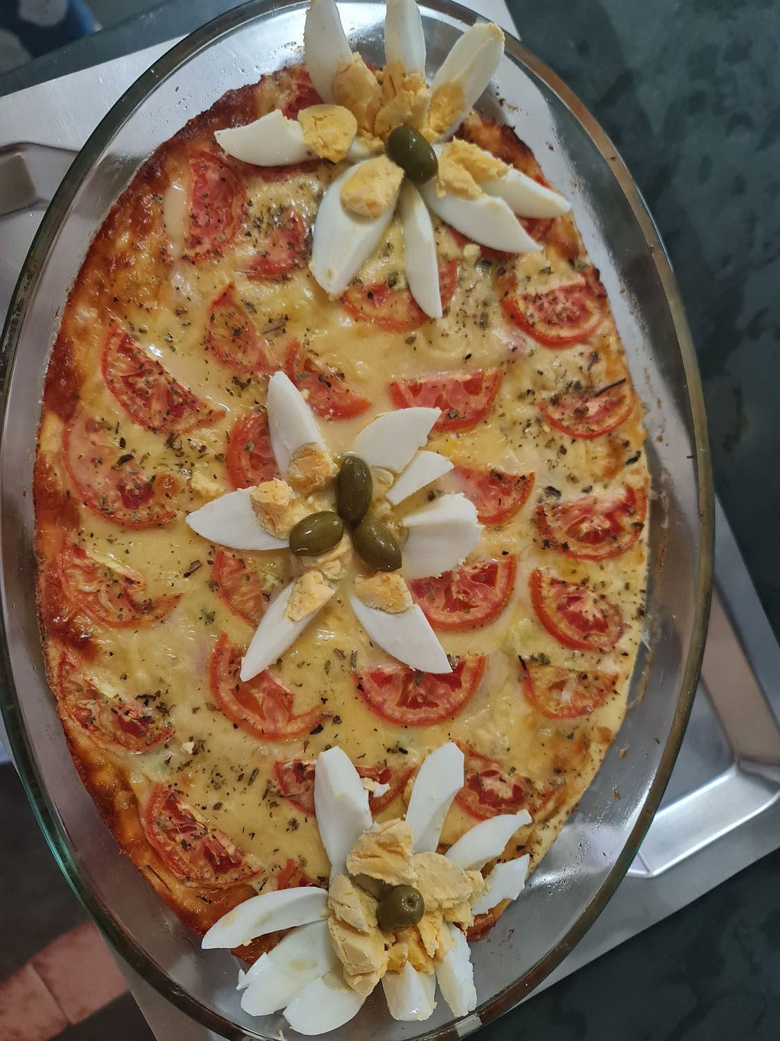 Uma pizza com tomates, ovos e azeitonas