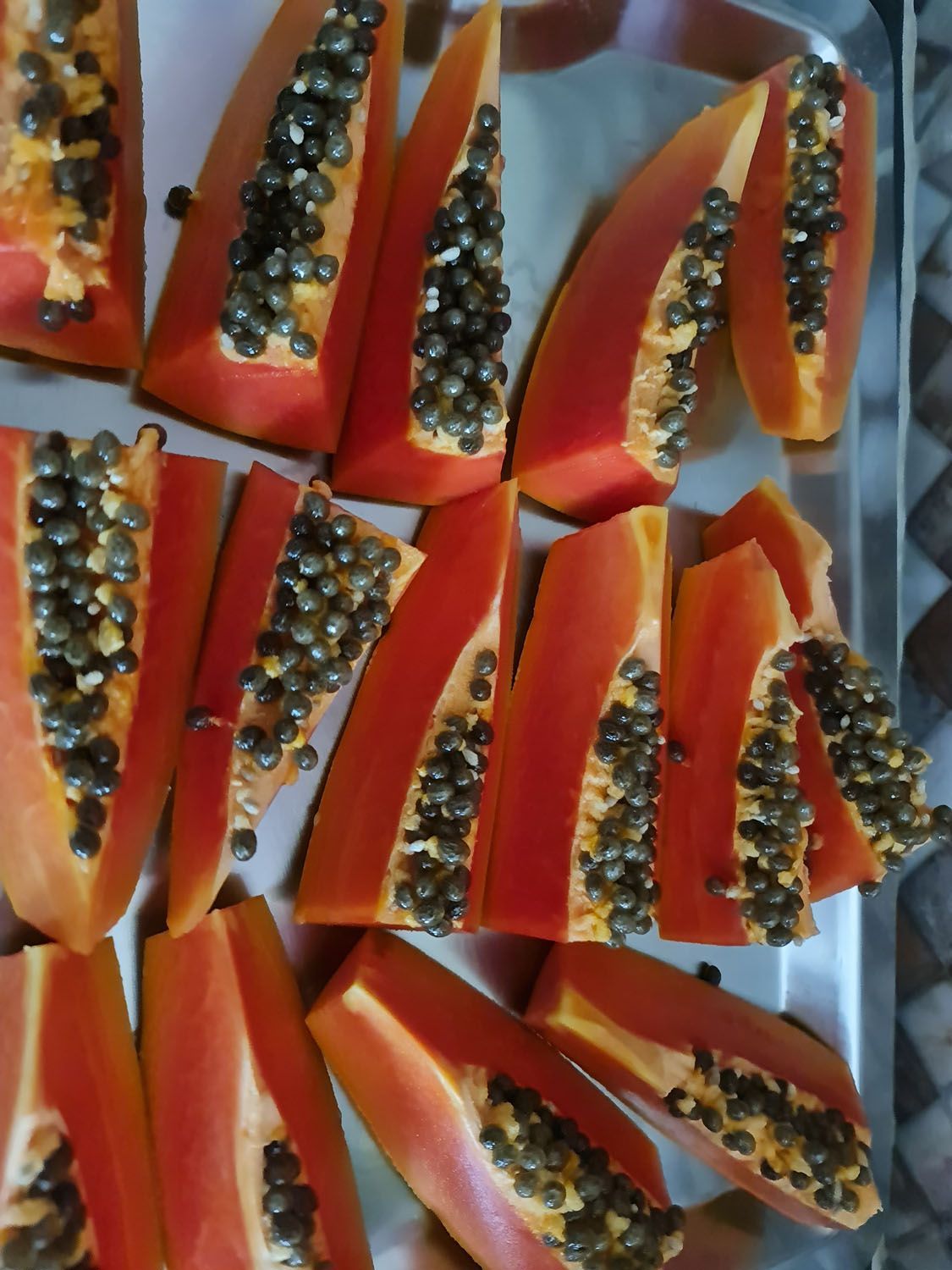 Um monte de fatias de mamão em uma bandeja de metal