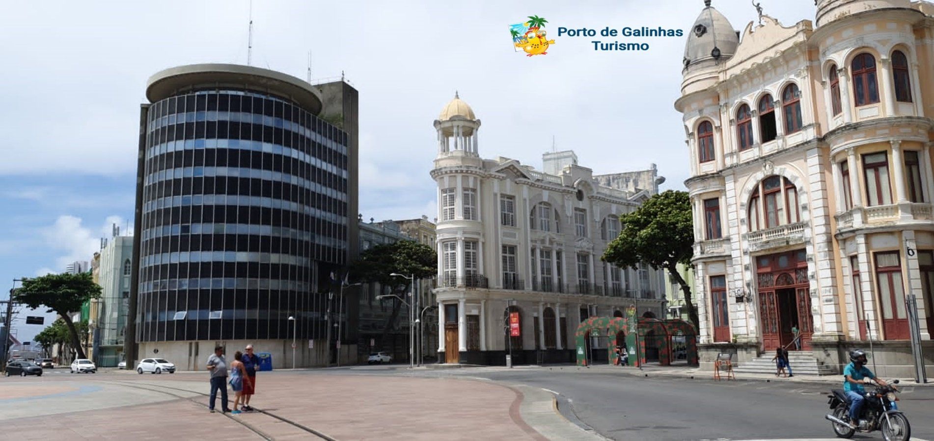 Um homem está pilotando uma motocicleta em frente a um grande edifício.