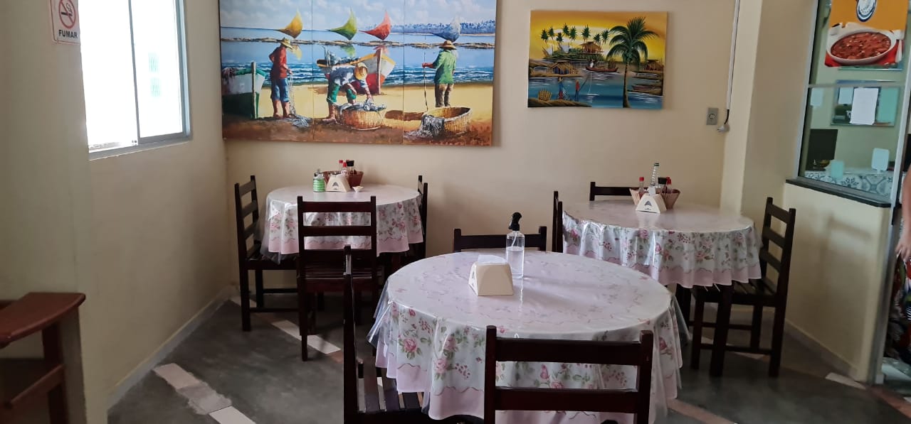 Um restaurante com mesas e cadeiras e uma pintura na parede.