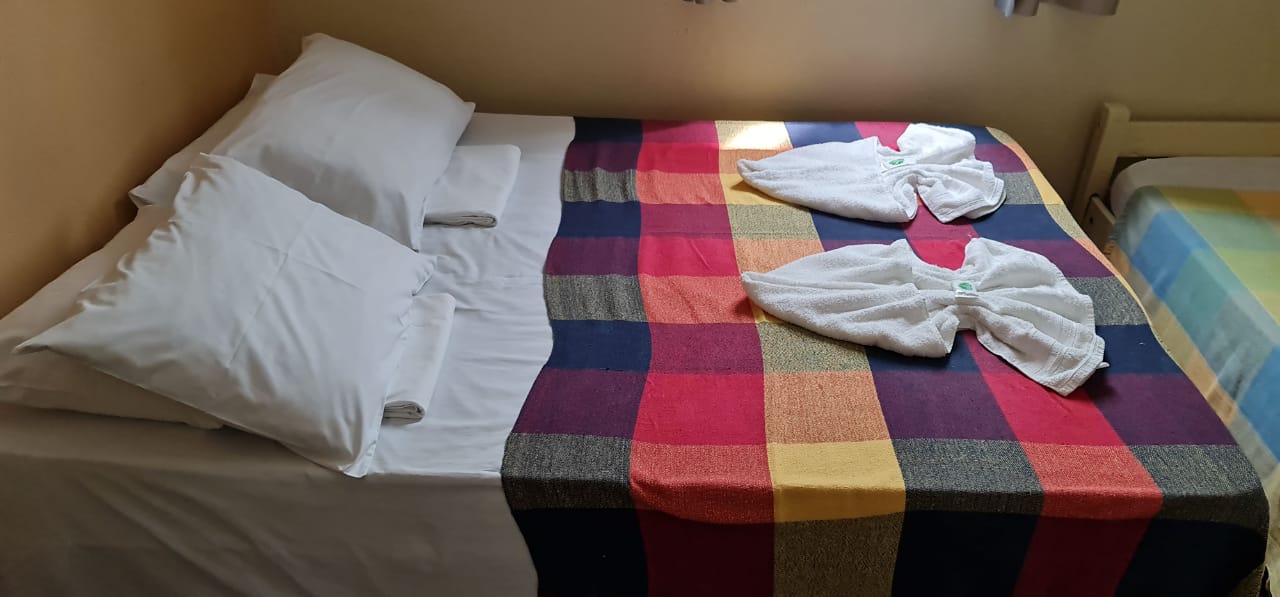 Uma cama com um cobertor xadrez e toalhas sobre ela