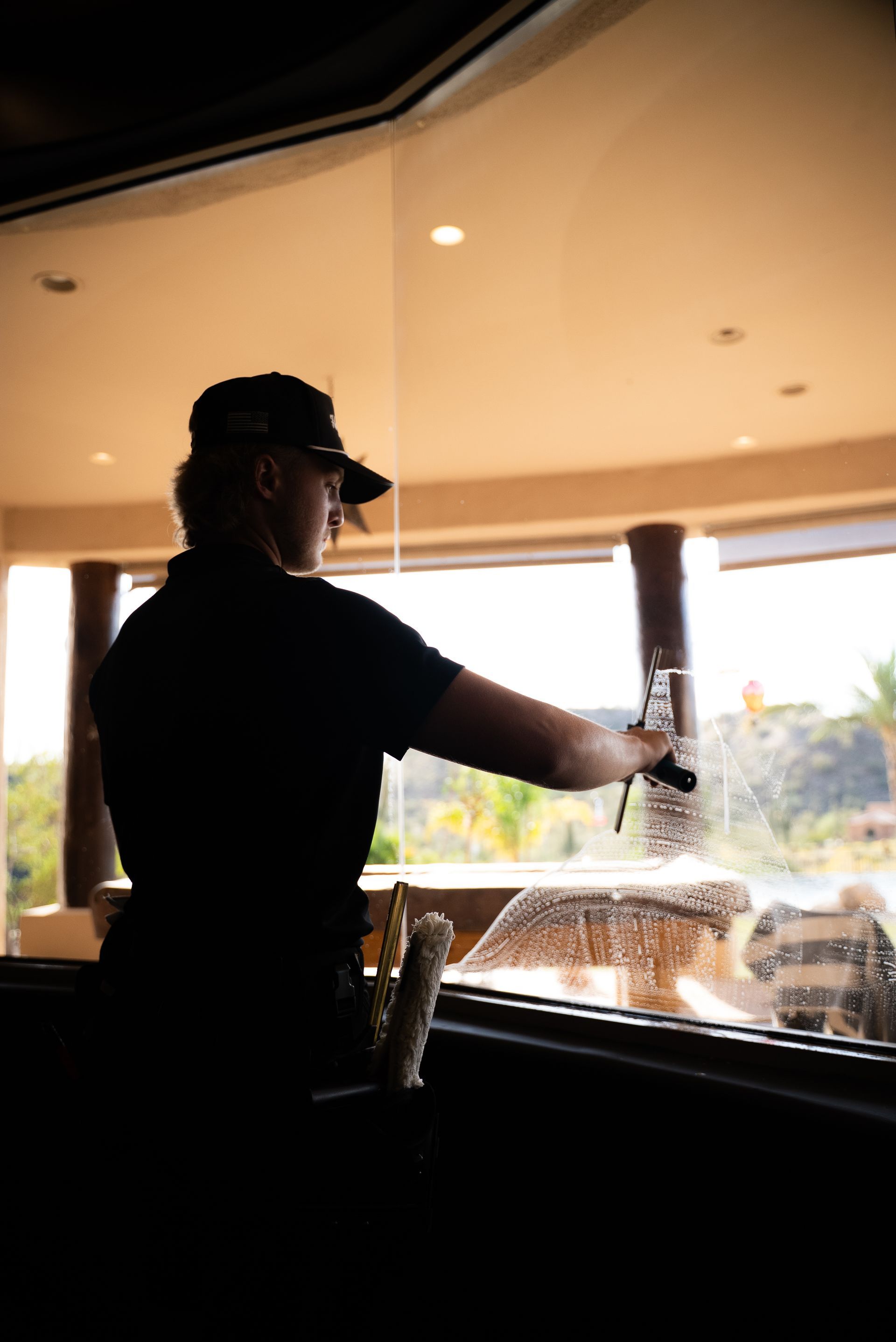 A man on a ladder is fixing a sign on the side of a building.