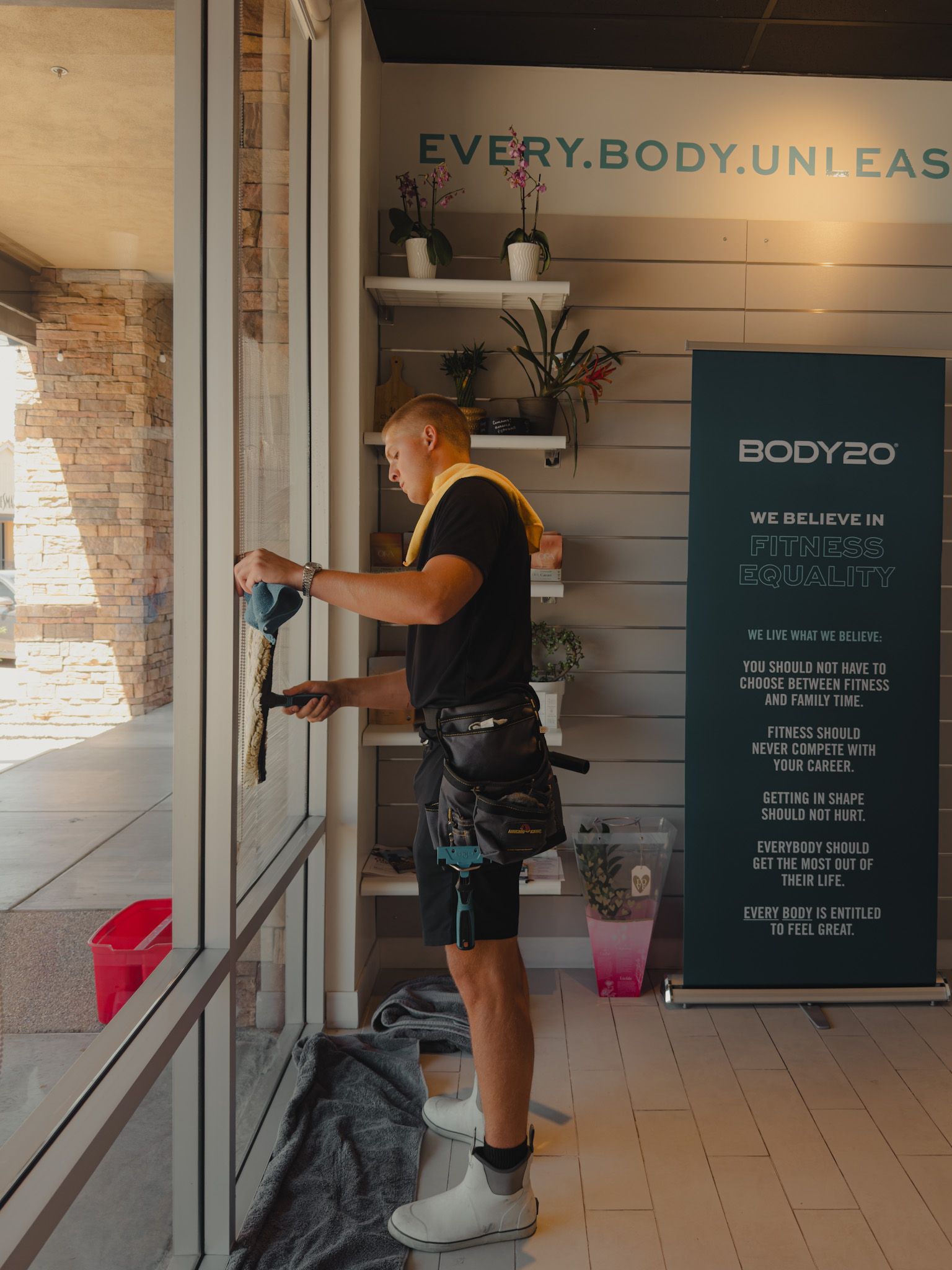 A man on a ladder is fixing a sign on the side of a building.