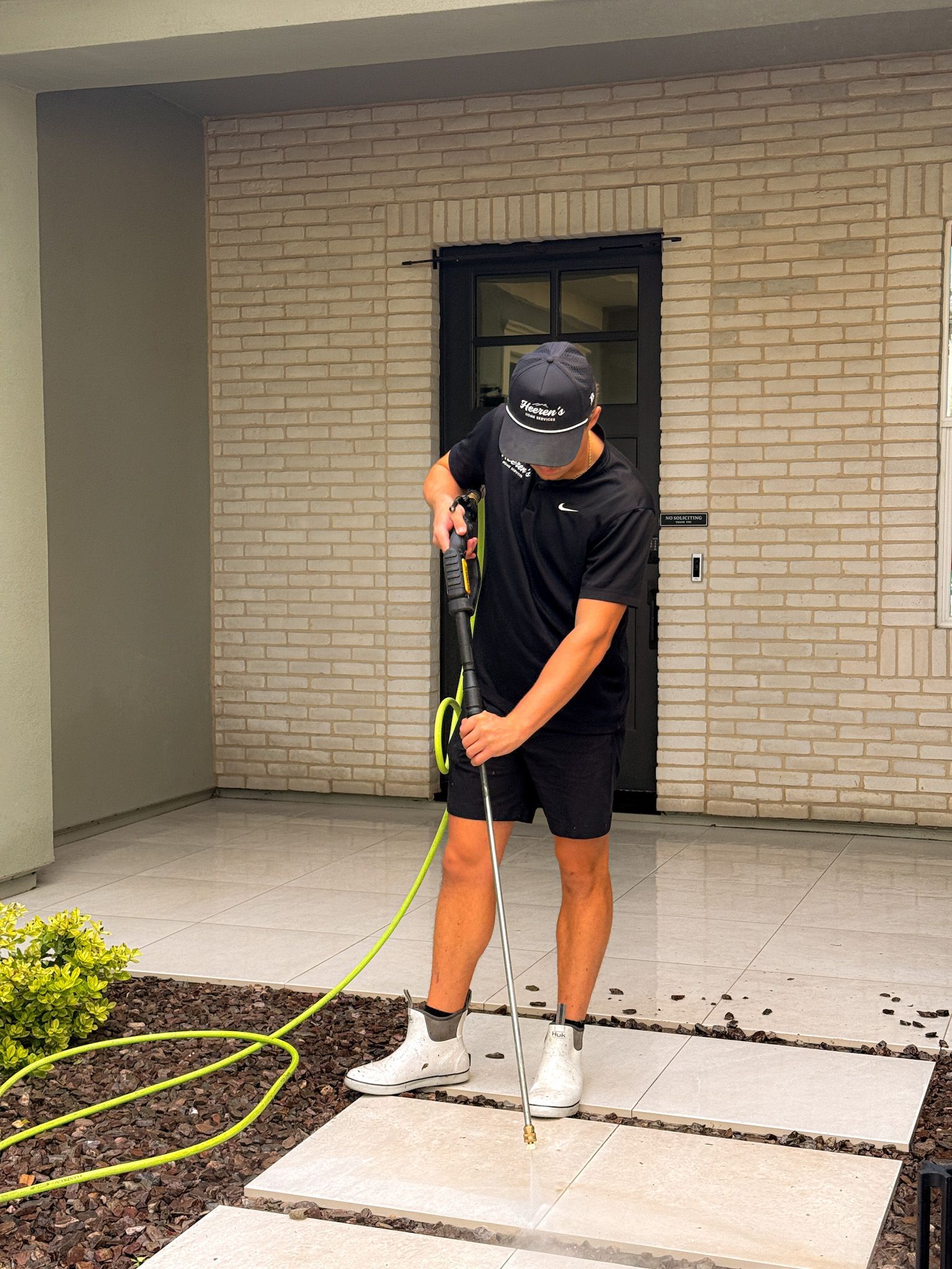 A man is standing on a patio in front of a large window.