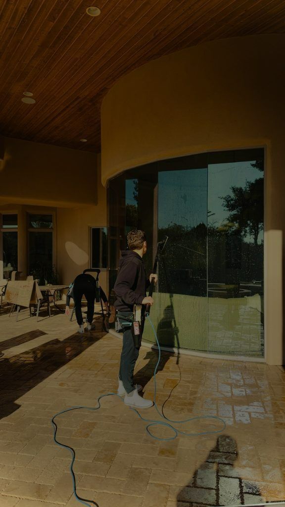 A man is standing on a patio in front of a large window.