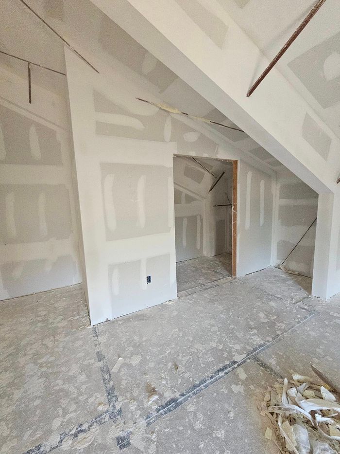 An empty room with a vaulted ceiling and drywall walls