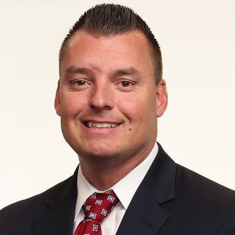 A man and a woman are sitting on a dock overlooking a lake.
