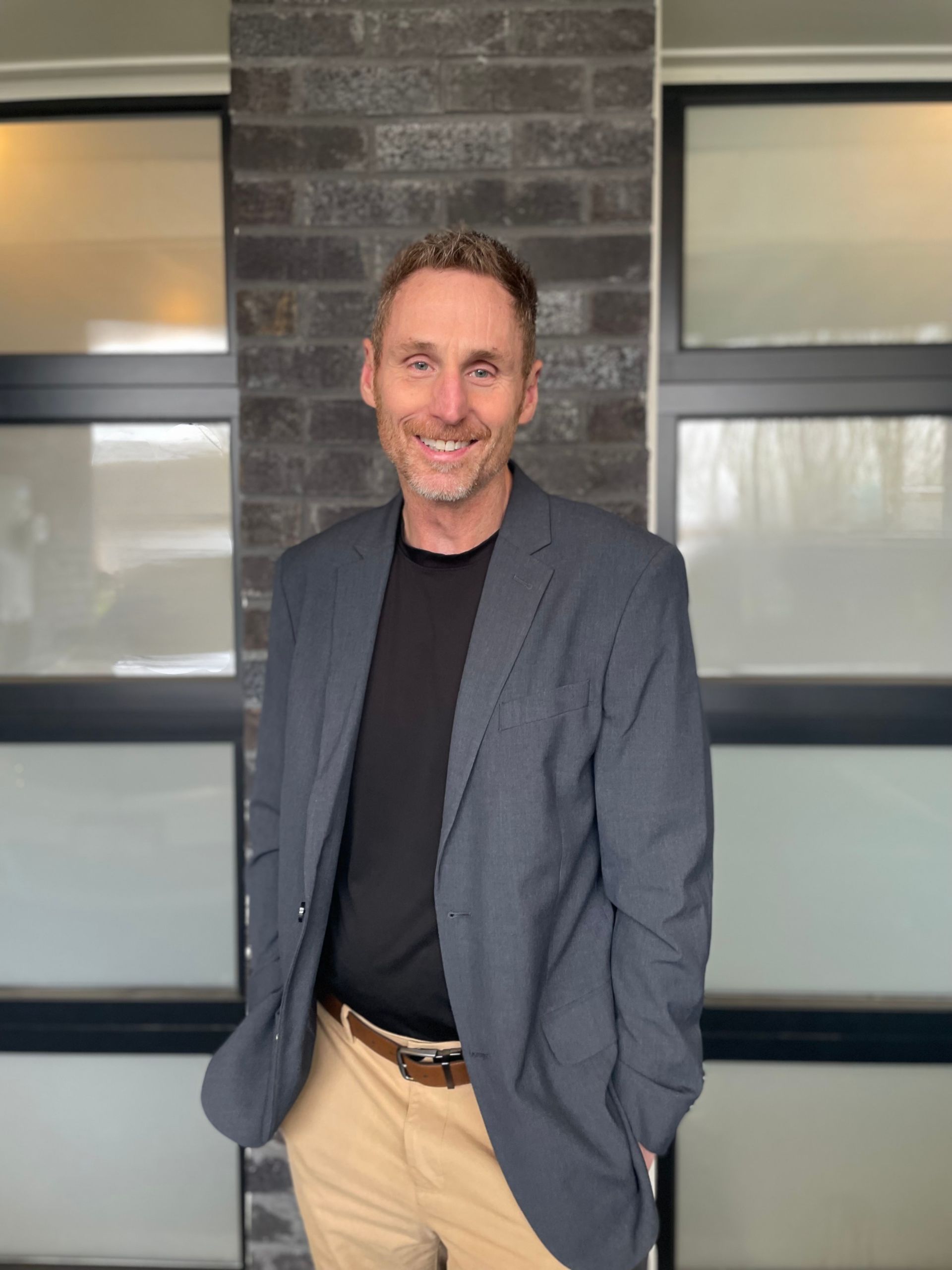 A woman is sitting at a desk with a laptop and a vase of flowers.