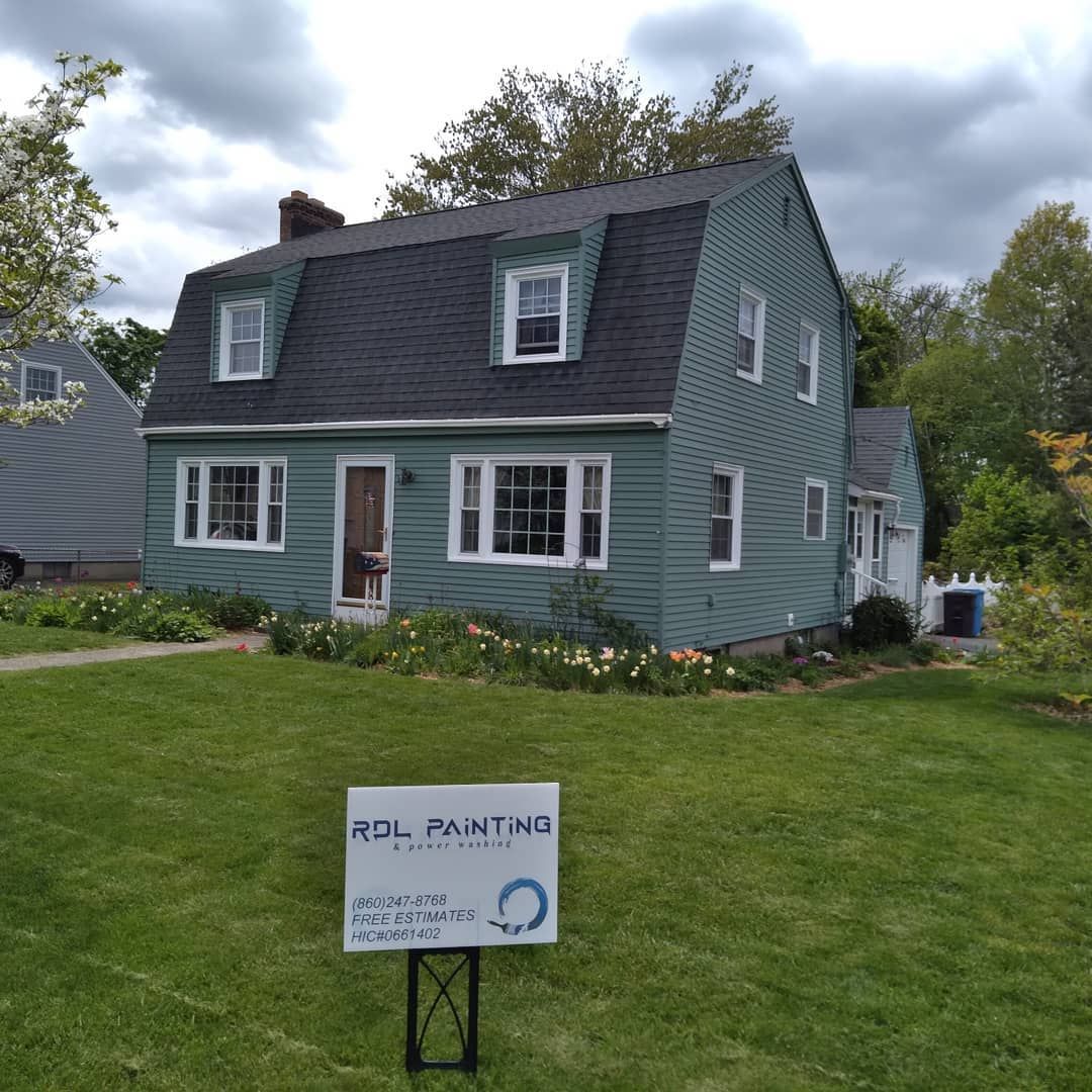 Teal house with white trim on a grassy lawn, with a small sign in front reading “No Parking.”