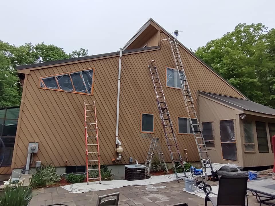 House exterior with steep roof, several ladders, and workers’ tools during maintenance or repair