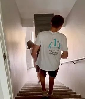 Two people carrying a large wooden board up a flight of stairs.