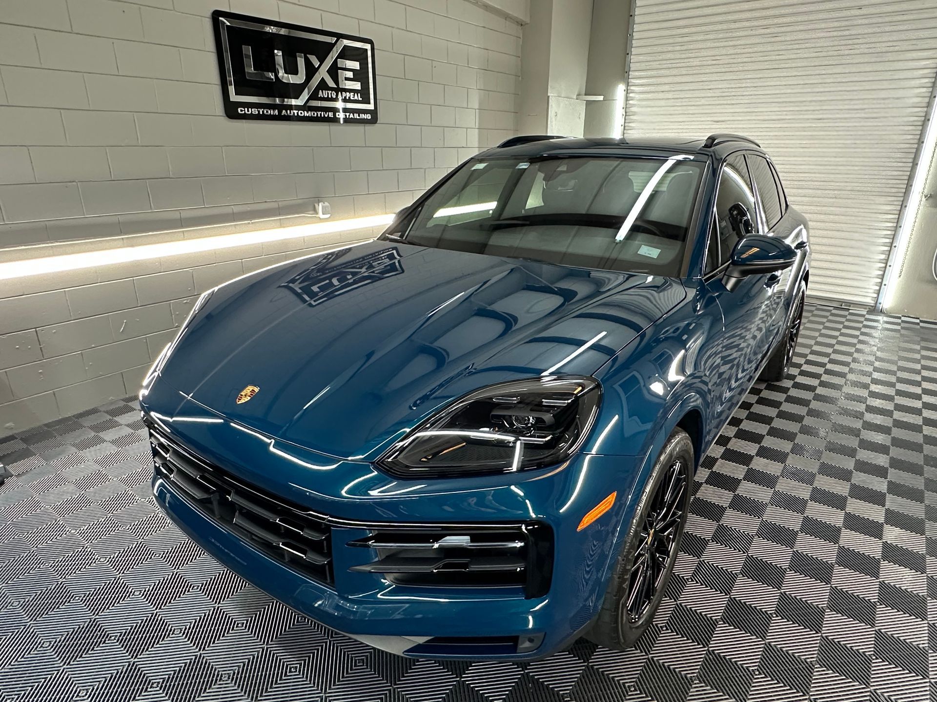 A blue porsche cayenne is parked in a garage.