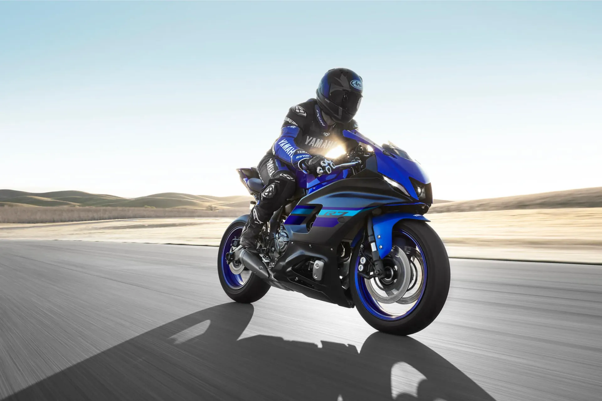 Ein Motorradfahrer in schwarzer Schutzkleidung fährt mit einem blauen Yamaha-Sportmotorrad