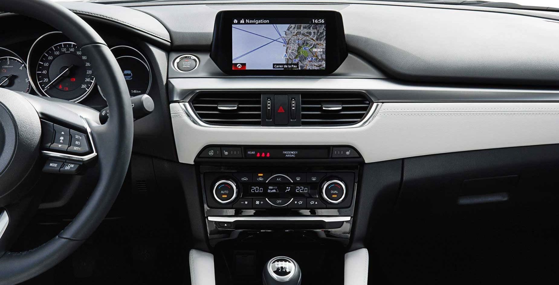 Das Armaturenbrett eines Autos mit Lenkrad, zentralem Infotainment-Bildschirm, Navigationskarte und Klimareglern.